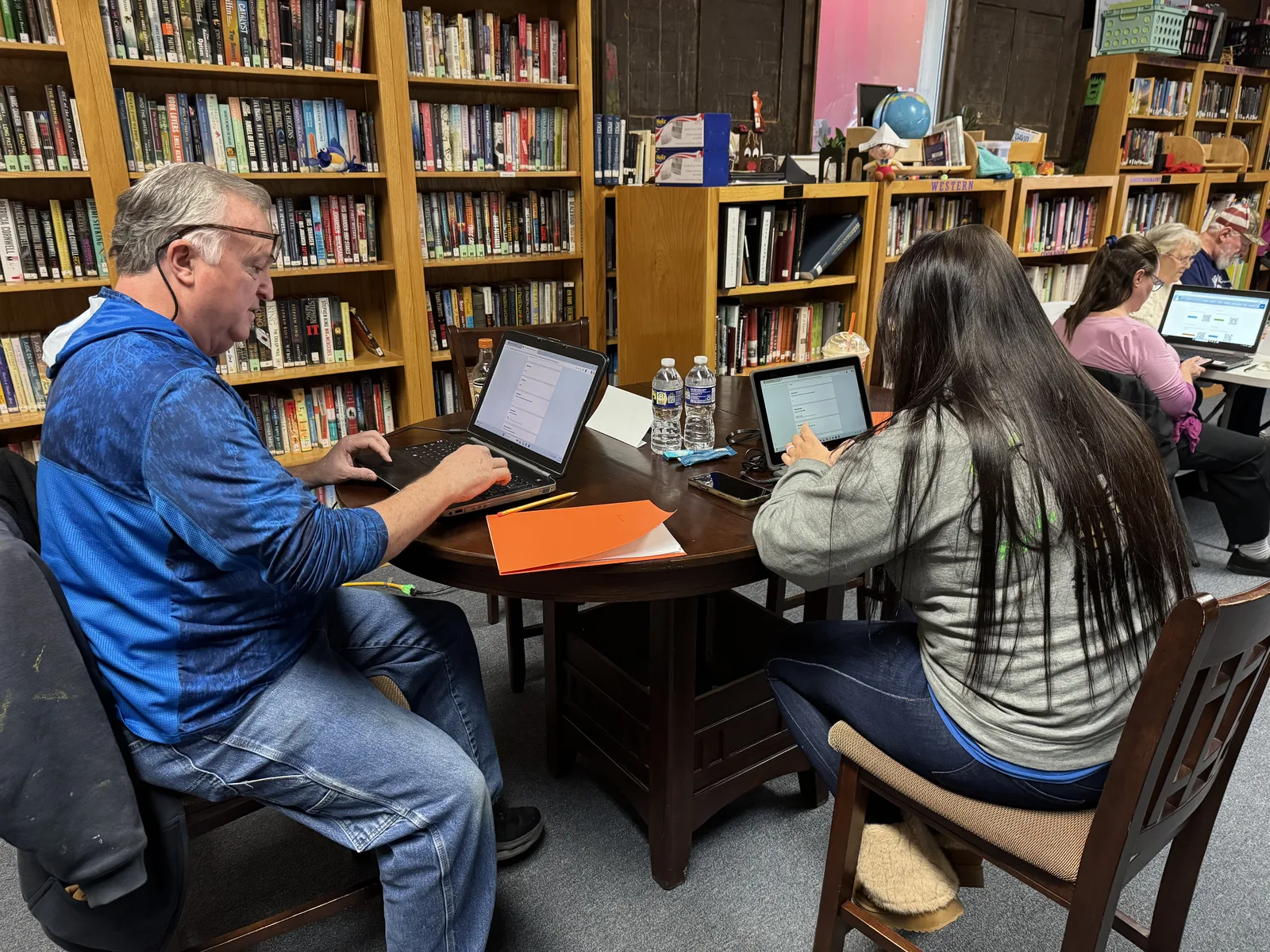 Instructor helping adult learners during a library-based technology class